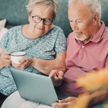 A couple on a sofa managing a memorial tribute page online